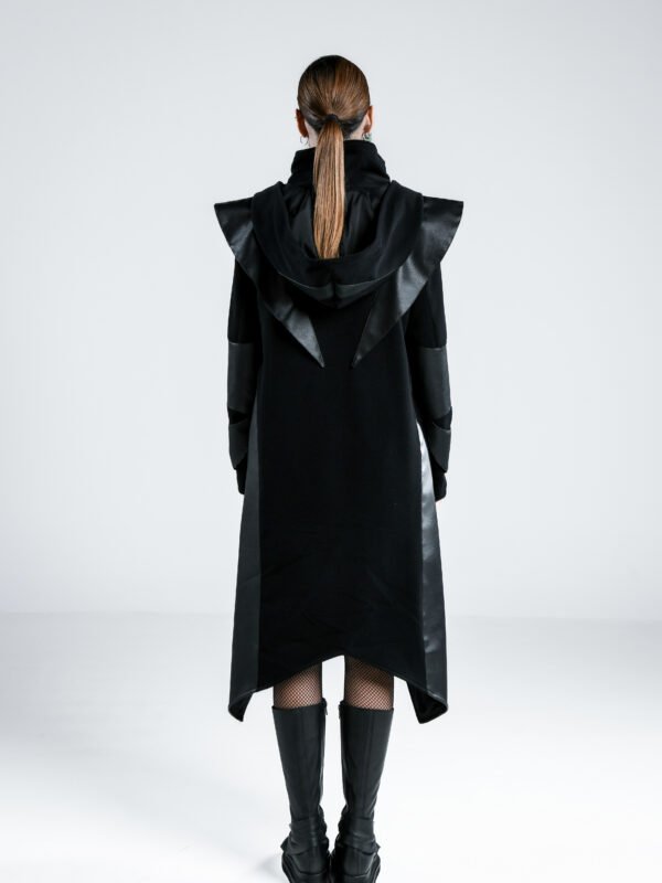 Back view of the Ashfall Coat, women's black long coat with oversized hood, faux-leather shoulder detailing and asymmetric hem.