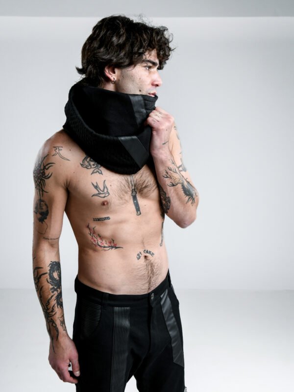 Axiom unisex black wrap scarf styled around a man's neck, showing its layered shape and textured panels.